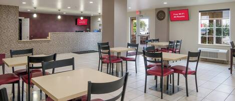 A restaurant with multiple tables and chairs, a reception desk, and a sign indicating free Wi-Fi availability.
