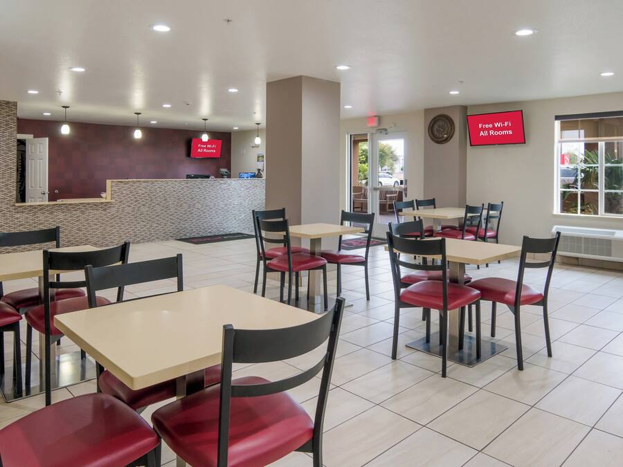 Un restaurante con varias mesas y sillas, un mostrador de recepción e indicación de Wi-Fi gratuito.