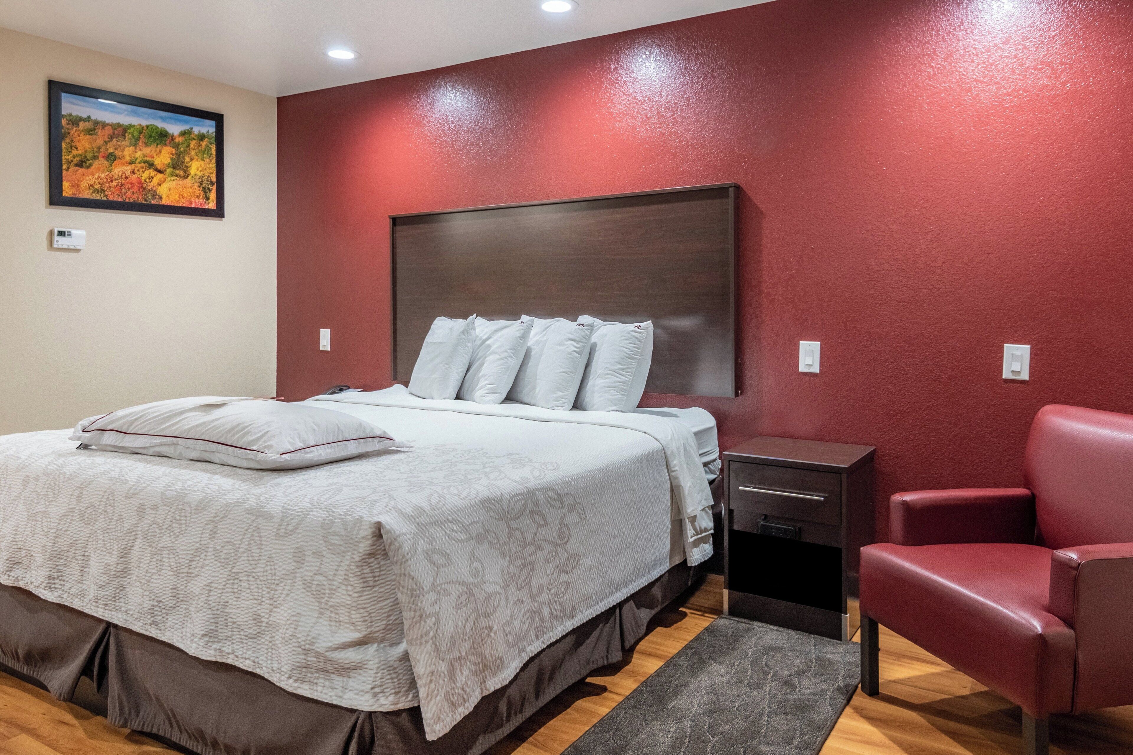 A bedroom with a bed, bedside tables, a chair, and a painting on the wall.
