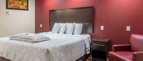 A bedroom with a bed, bedside tables, a chair, and a painting on the wall.