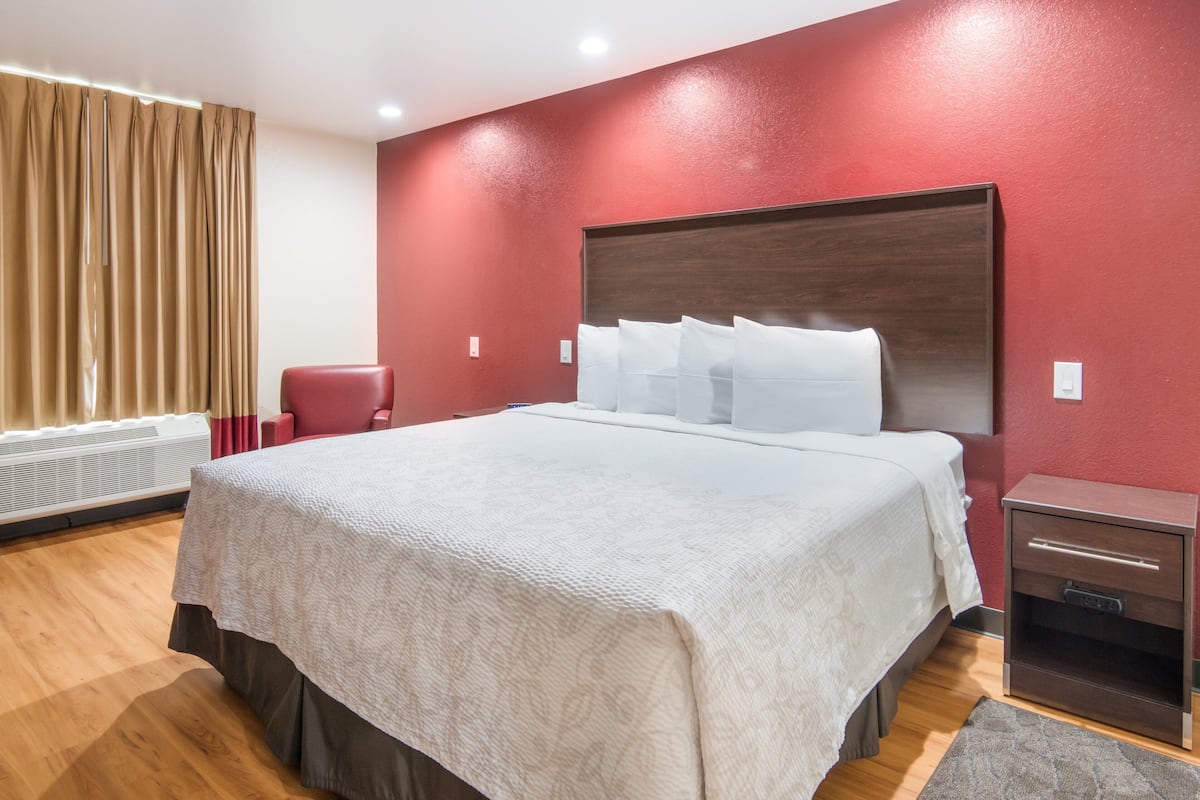 A neatly made bed with white linens, a wooden headboard, and a nightstand with drawers.