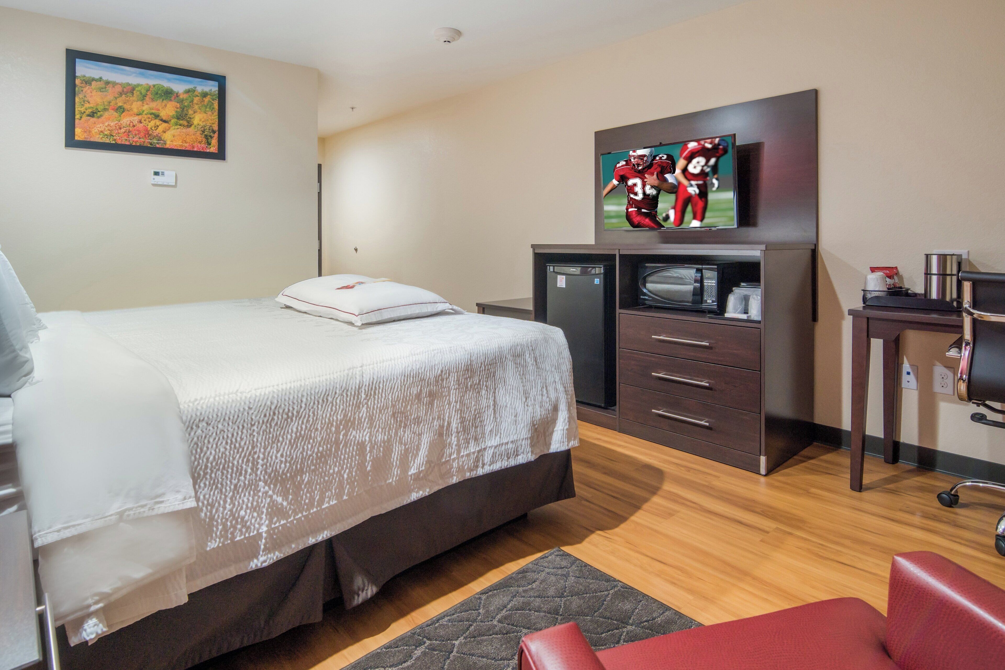 Una habitación de hotel con cama, televisión, escritorio y silla.