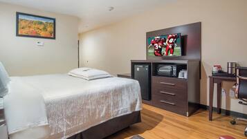 Una habitación de hotel con cama, televisión, escritorio y silla.