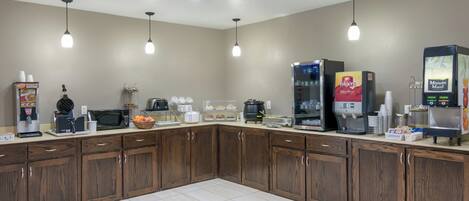 A commercial kitchen with various appliances, including a coffee machine, a microwave, and a food display.