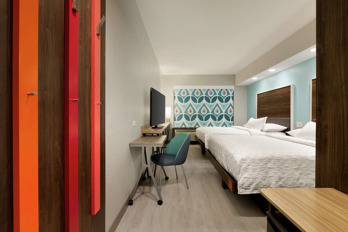 Una habitación de hotel con una cama, un escritorio con computadora, una silla y un televisor.