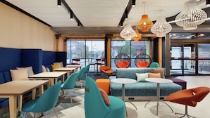 A modern lounge area with seating arrangements, tables, and hanging pendant lights. - Tru by Hilton St. Charles St. Louis, MO (St. Charles)