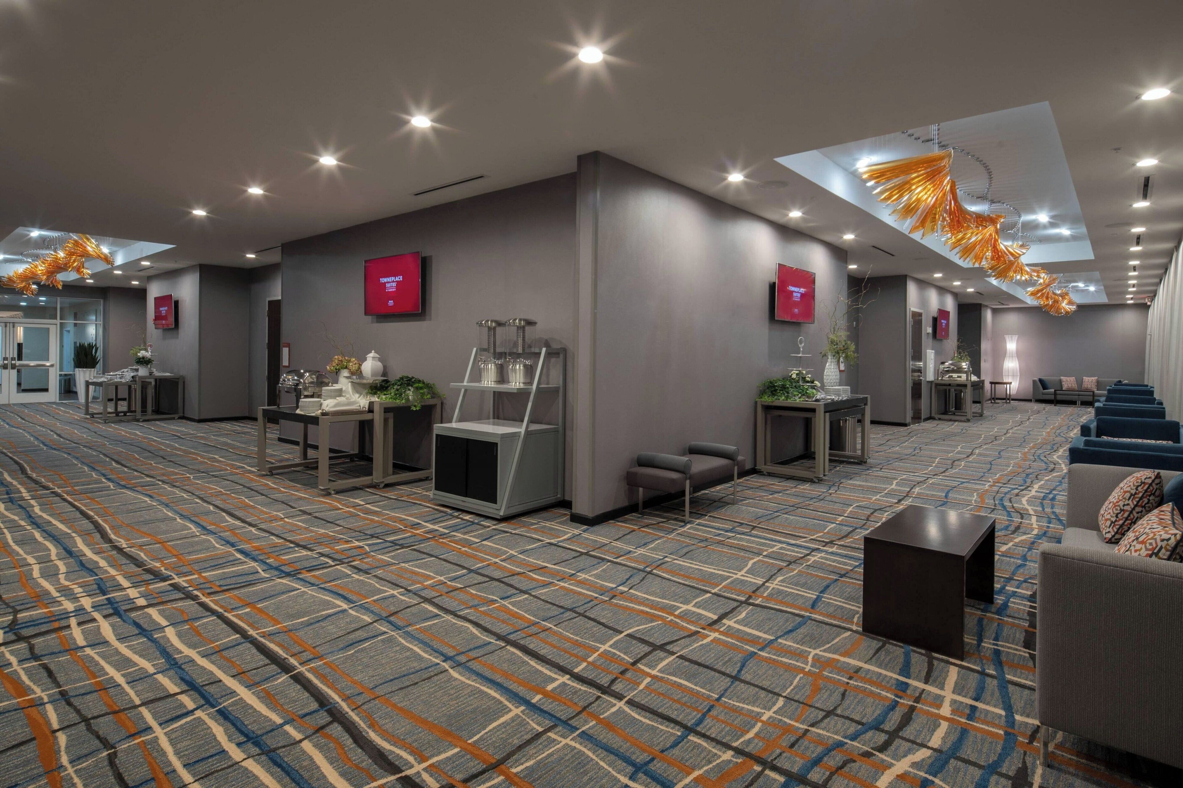 A spacious hotel lobby with a patterned carpet, seating areas, and modern decor.