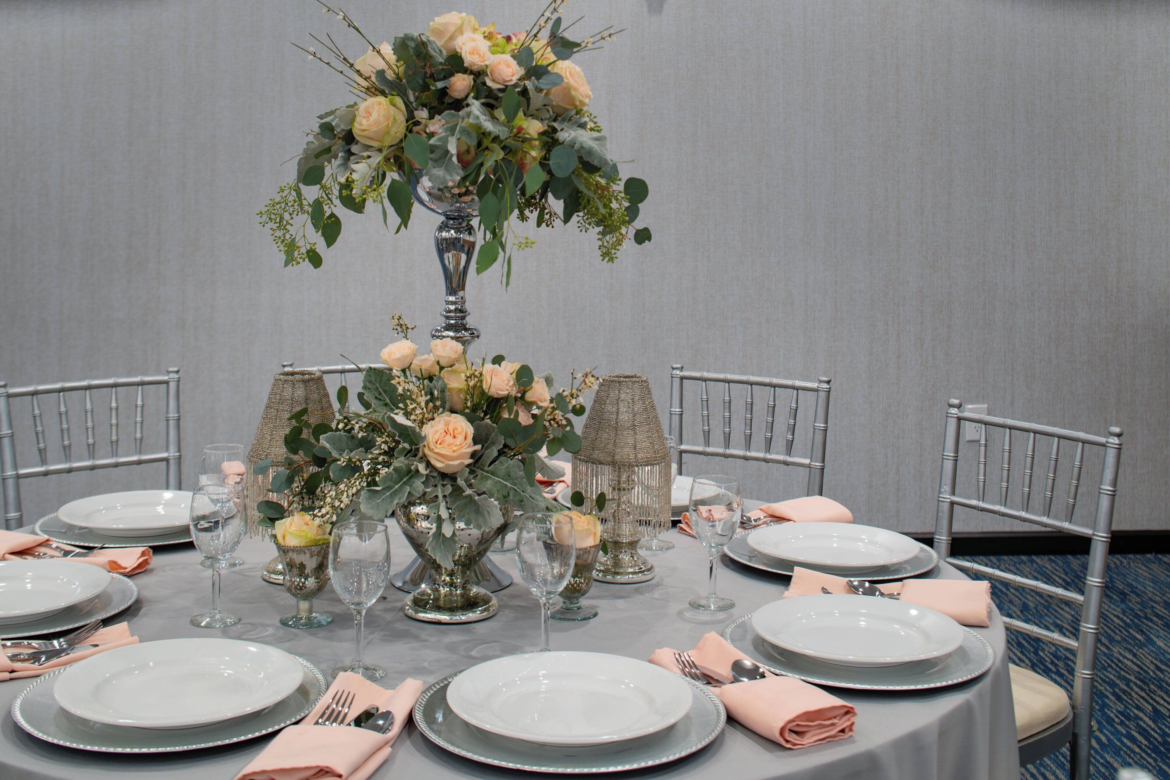A table set for a formal dinner with multiple plates, cutlery, and a centerpiece of flowers.