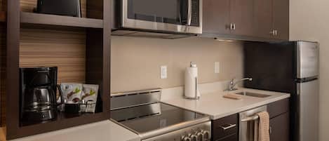 Una cocina moderna con electrodomésticos de acero inoxidable, microondas integrado y cafetera.