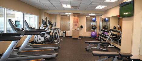 A gym with treadmills, elliptical machines, and weight benches.