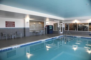 Una piscina interior con agua cristalina, una estación de socorristas y un letrero que advierte sobre la presencia de salvavidas.