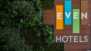 A hotel sign with the name 'EVEN HOTELS' in large letters, surrounded by greenery.