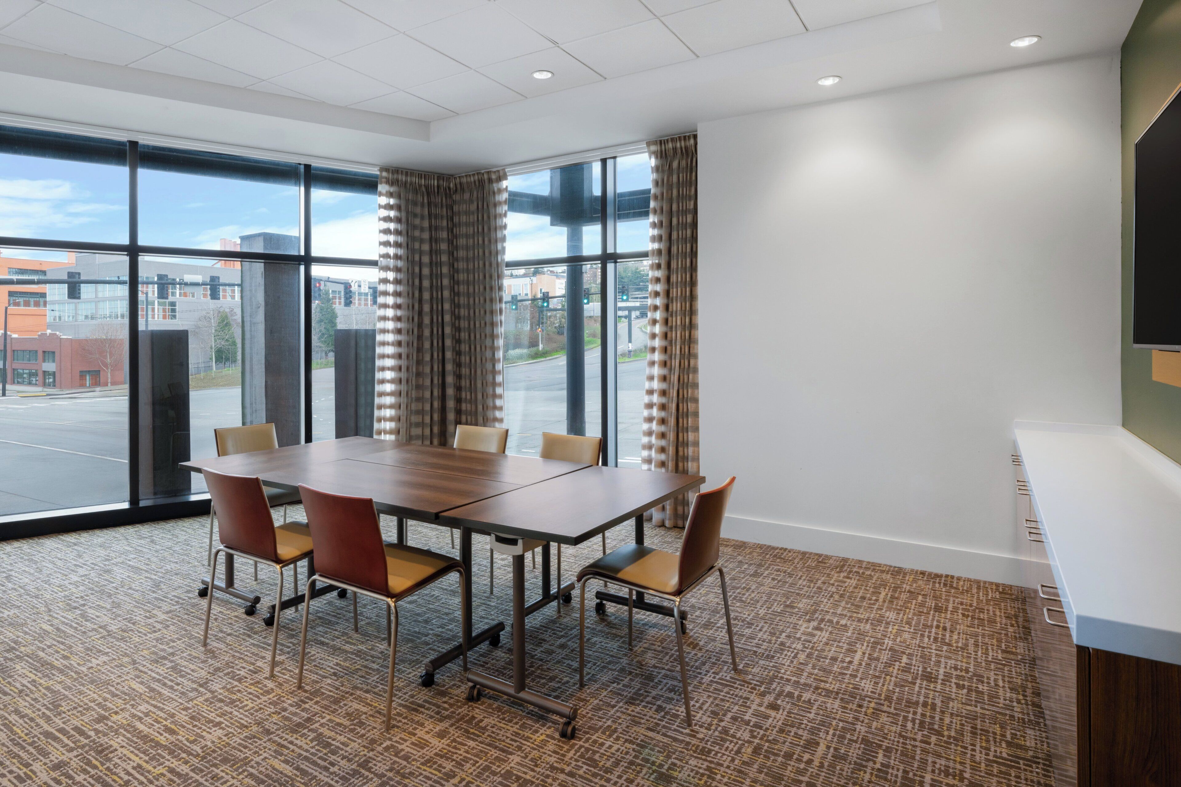 A conference room with a large table, chairs, and a view of the city through large windows.