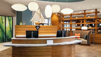 A reception desk with a wooden finish, a sailboat decoration, and pendant lighting.