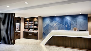 A modern reception area with a reception desk, a bookshelf, and a wall with geometric patterns. - SpringHill Suites by Marriott Albuquerque North/Journal Center (Albuquerque)