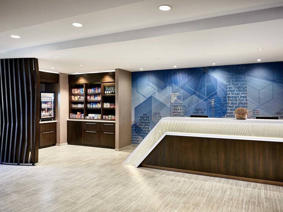 A modern reception area with a reception desk, a bookshelf, and a wall with geometric patterns.