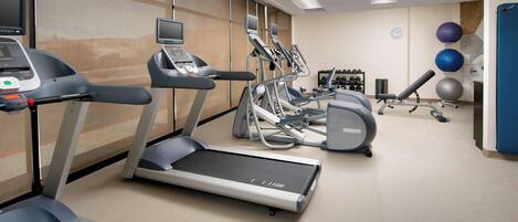 A fitness center with treadmills, elliptical machines, and exercise balls.
