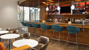 A bar area with a wooden bar counter, multiple stools, and a television screen. - Staybridge Suites Seattle Downtown - Lake Union by IHG (Seattle)