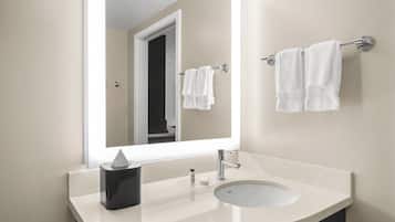 Un baño moderno con un espejo grande, un lavamanos y un perchero para toallas.