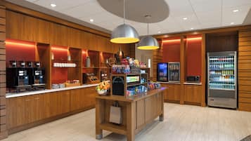 A hotel lobby with a coffee station, vending machines, and a microwave.