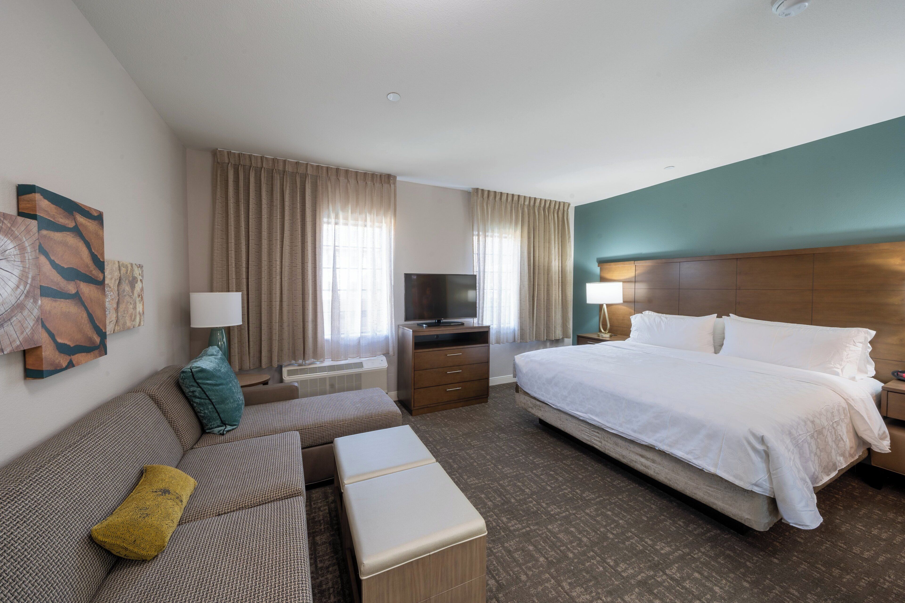 A hotel room with a bed, a sofa, a TV, and a desk.
