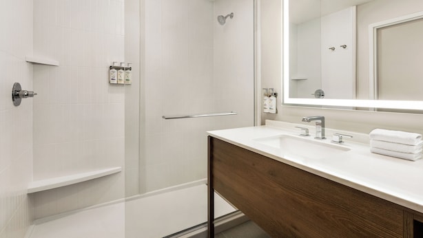 Un baño moderno con ducha, tocador con espejo y lavamanos.