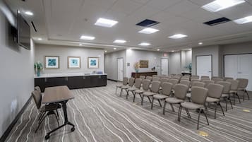 A conference room with a long table, chairs, a reception desk, framed artwork, and a carpeted floor.