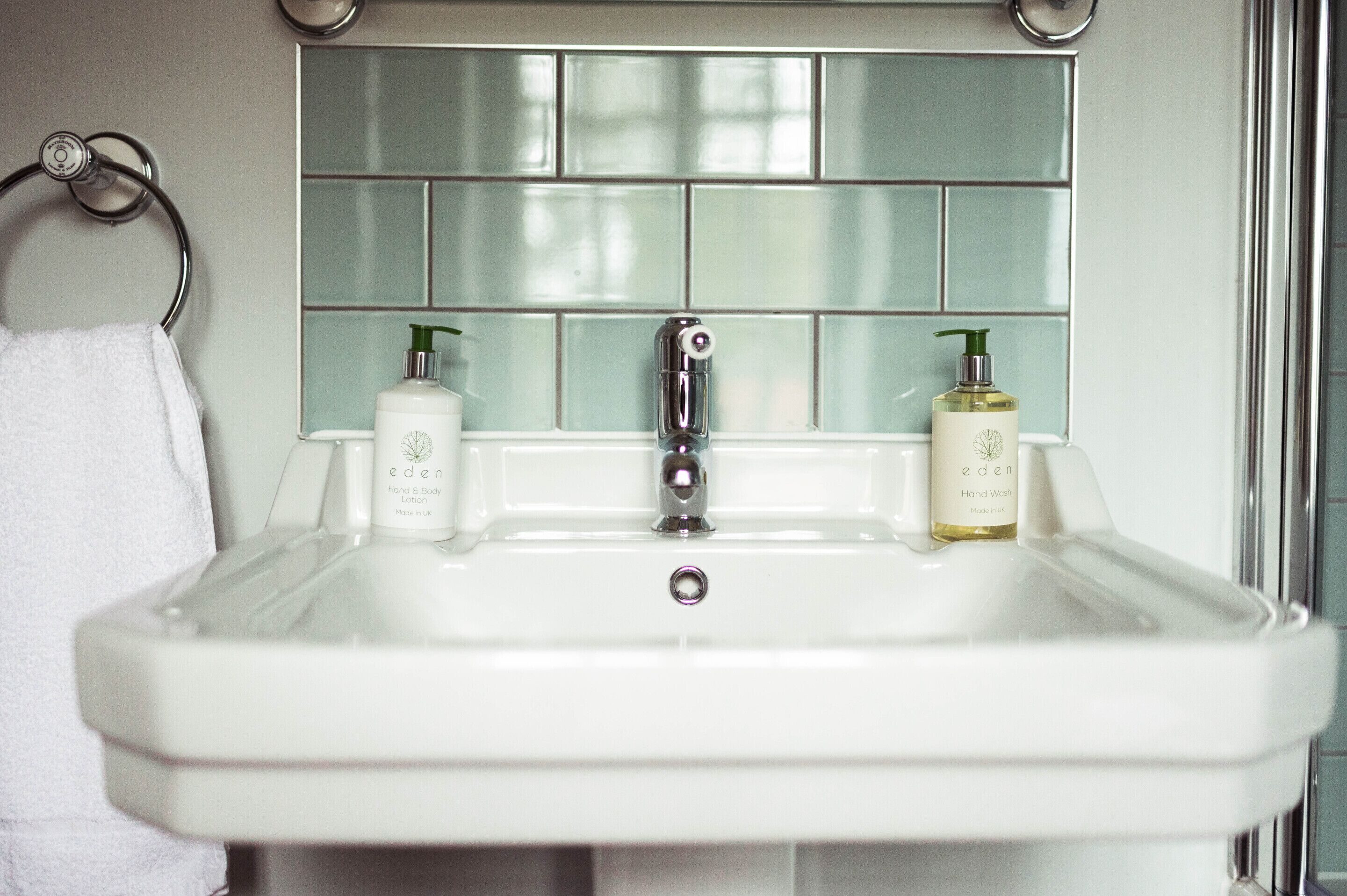 A bathroom with a white sink, two hand soap bottles, and a towel hanging on a metal ring.
