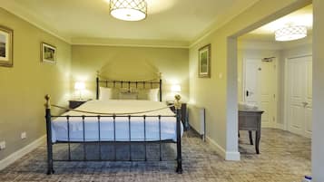 Un dormitorio con una cama con dosel, dos lámparas de noche, una mesita de noche y suelo alfombrado.
