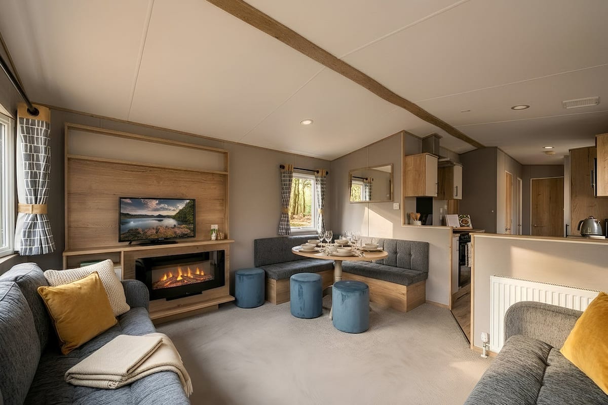 A modern living room with a fireplace, seating area, and kitchen.