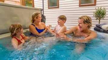 A family in a hot tub with a house in the background.