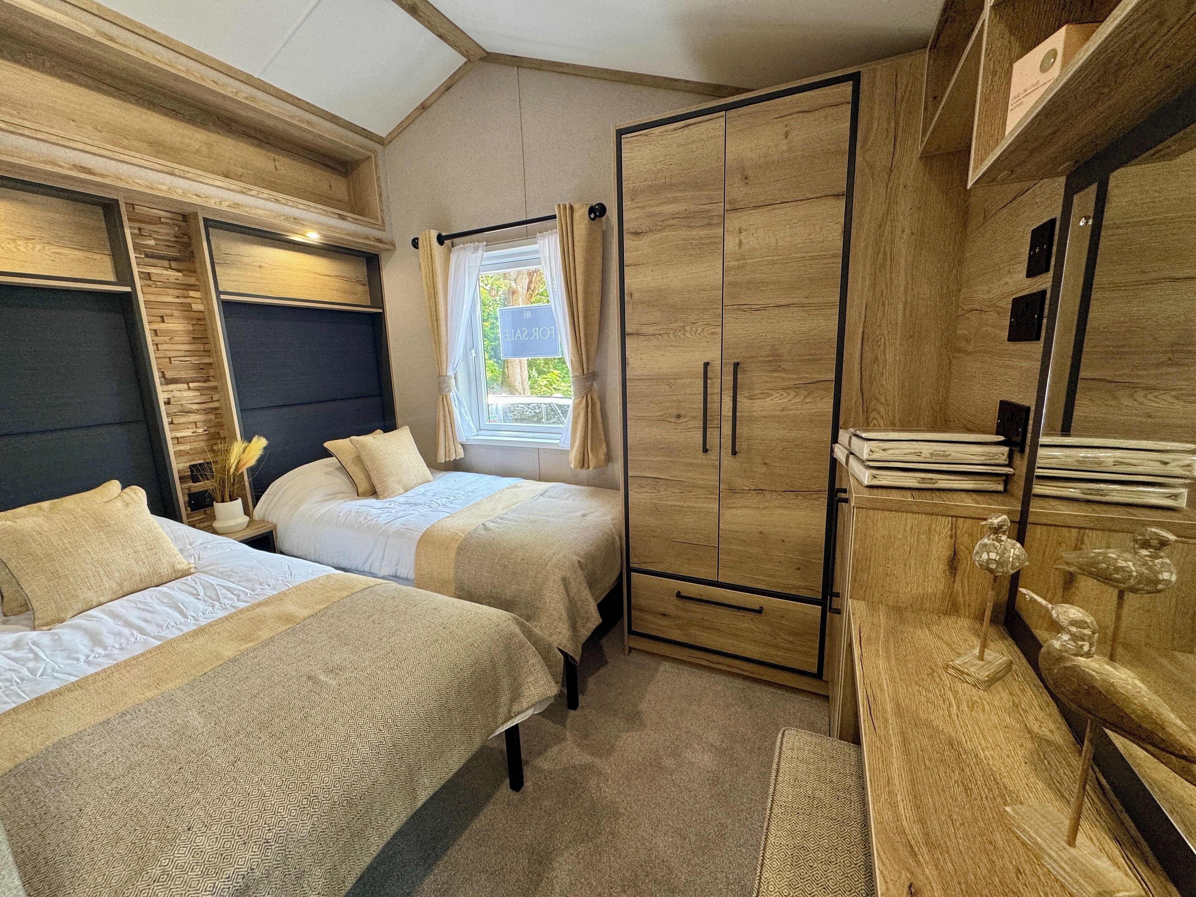 A bedroom with two beds, a wardrobe, and a window with curtains.