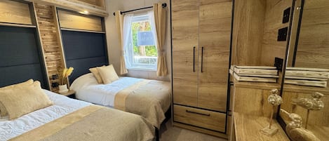 A bedroom with two beds, a wardrobe, and a window with curtains.