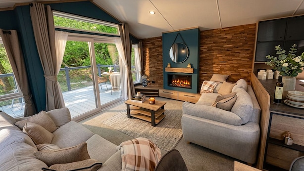A modern living room with a fireplace, comfortable seating, and a view of the outdoors. - Aberdunant Caravans Direct (Porthmadog)