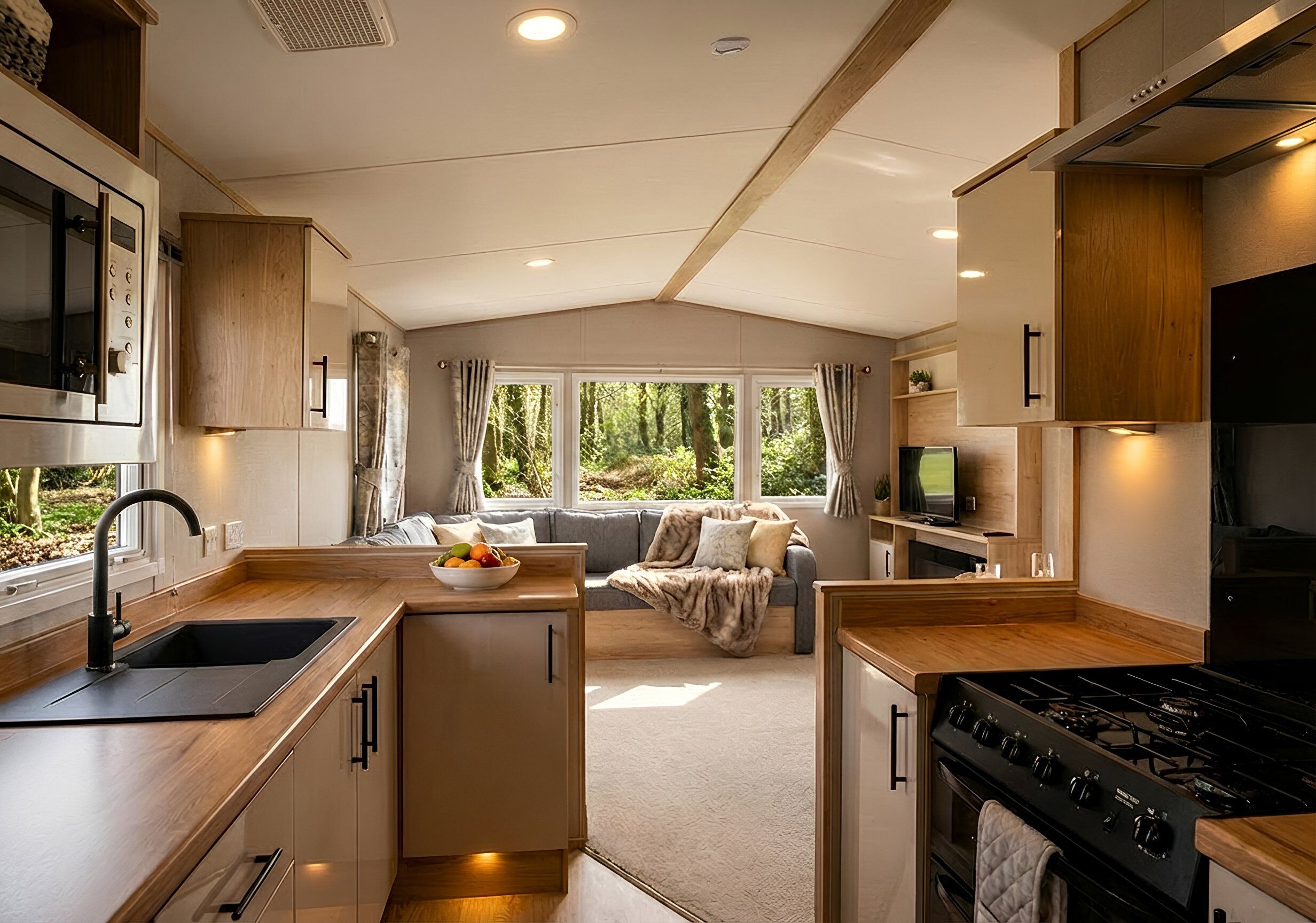 A modern kitchen with a built-in stove, a sink, and a dining area with a sofa and a TV.