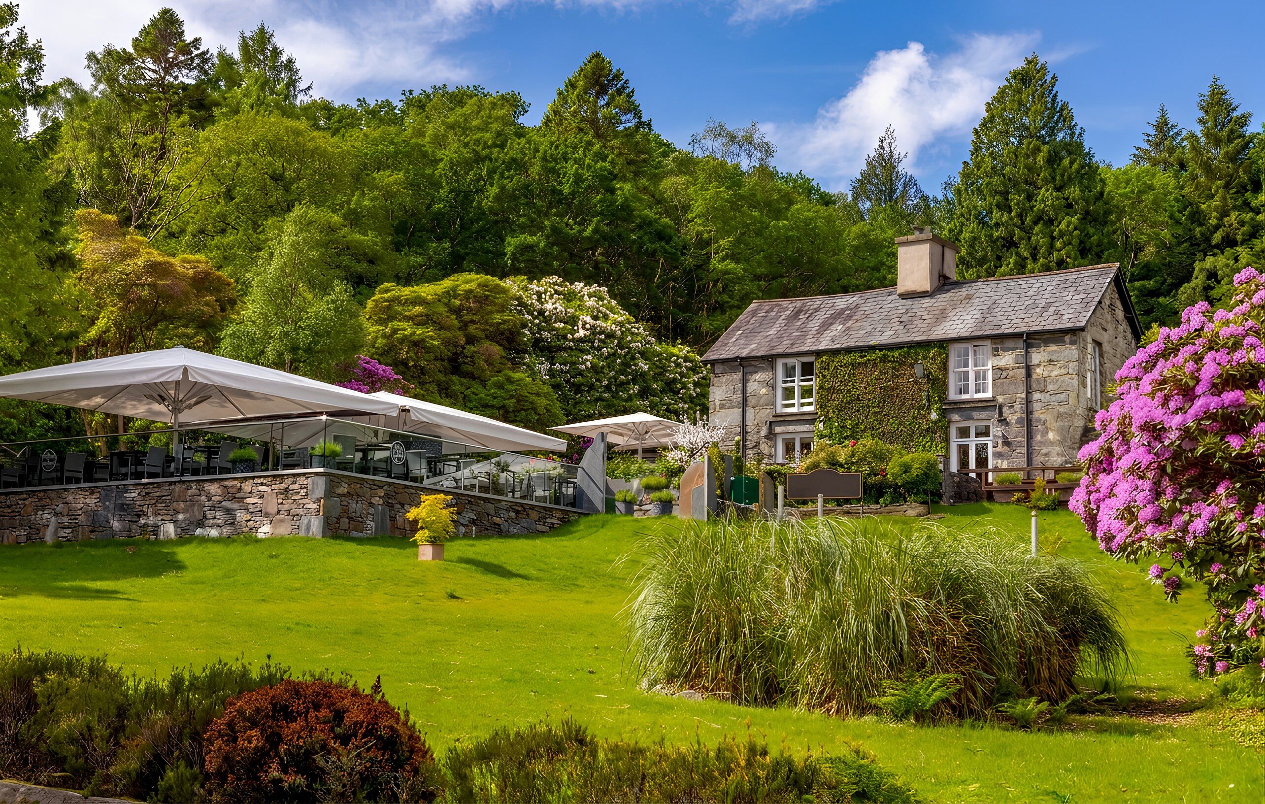 A stone building with a garden, a covered outdoor seating area, and a view of the surrounding greenery.