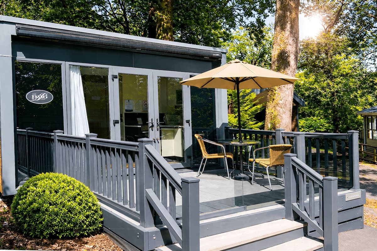 A small, modern outdoor seating area with a deck, a table, and two chairs.