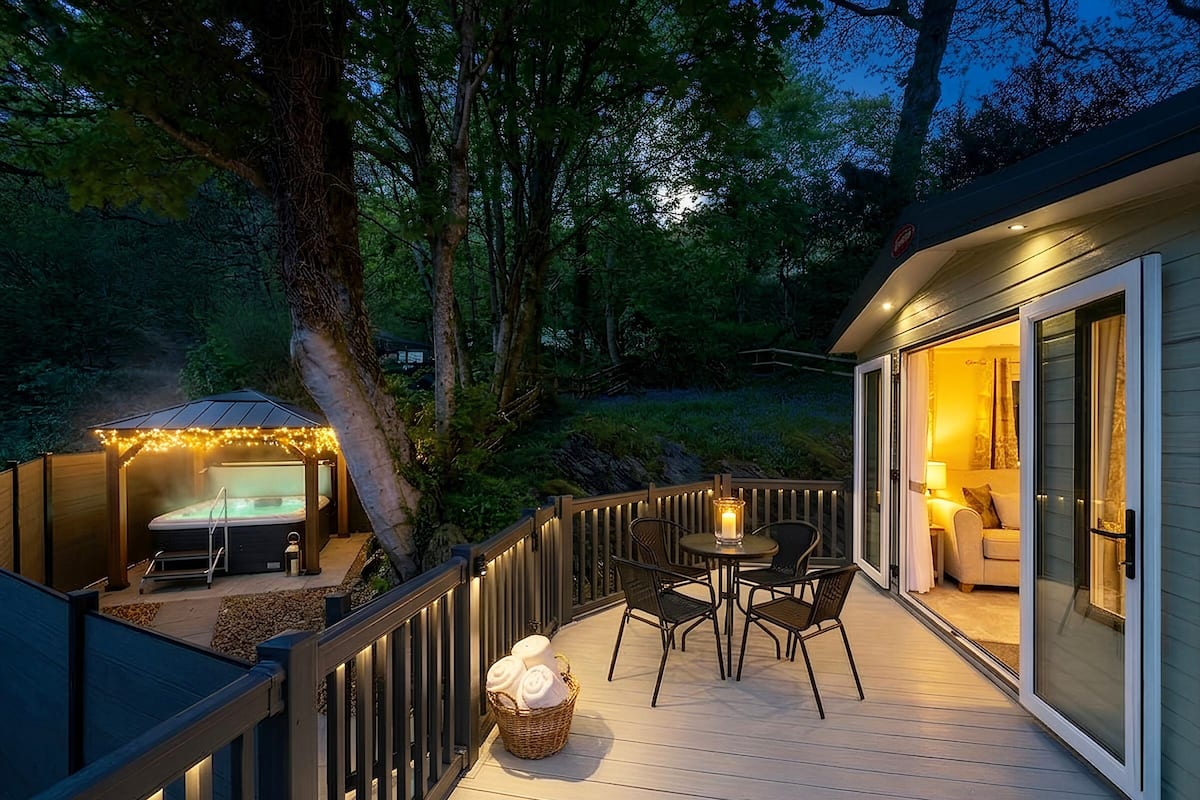 A deck with outdoor seating, a hot tub, and a building with a glass door.