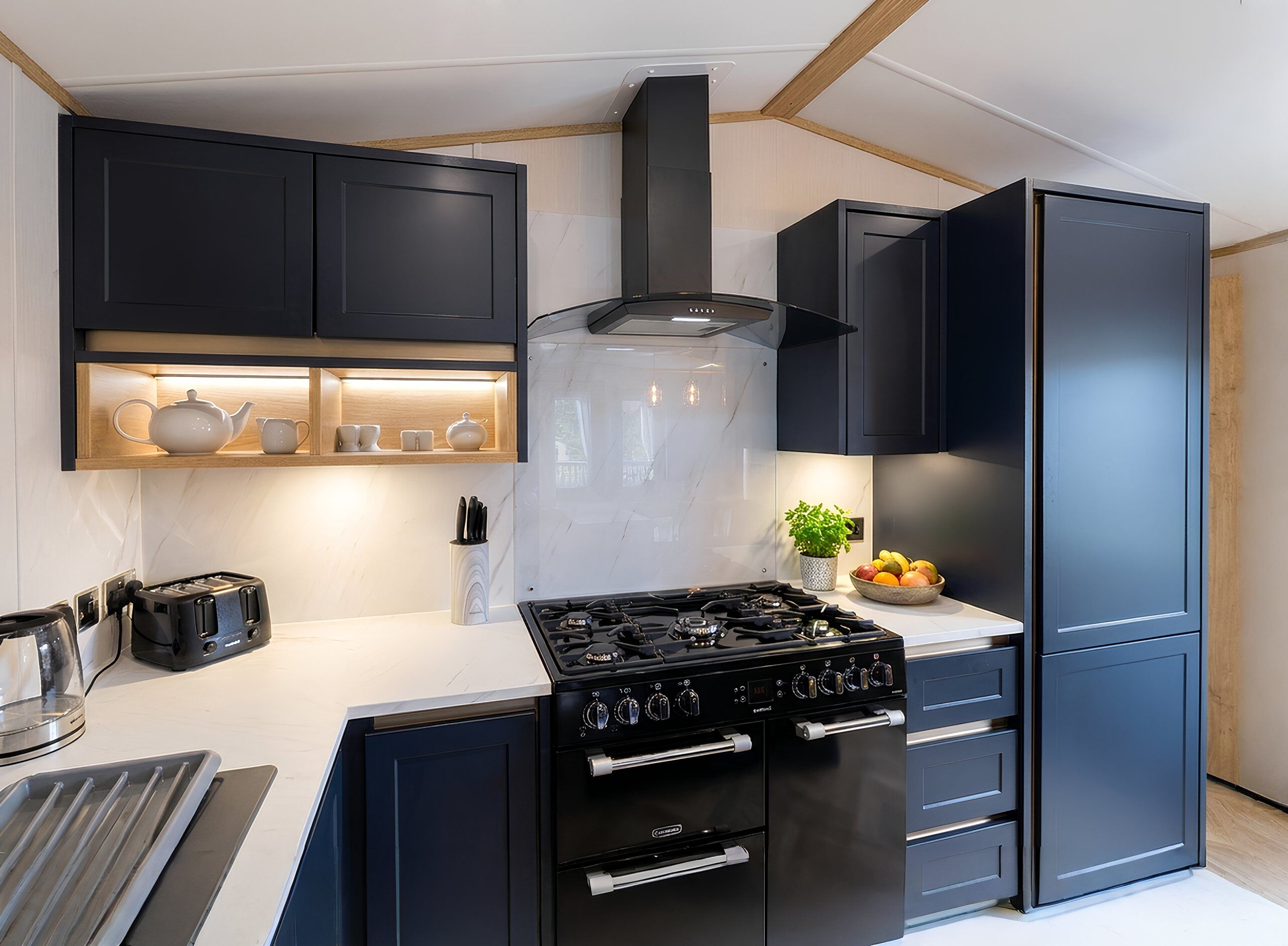 A modern kitchen with black cabinets, a gas stove, a built-in oven, and a refrigerator.
