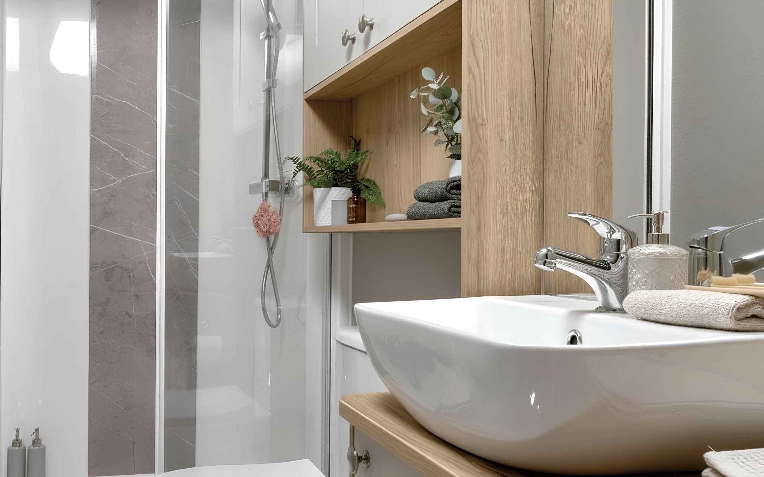 A modern bathroom with a large sink, a shower, and a wooden shelf with toiletries.