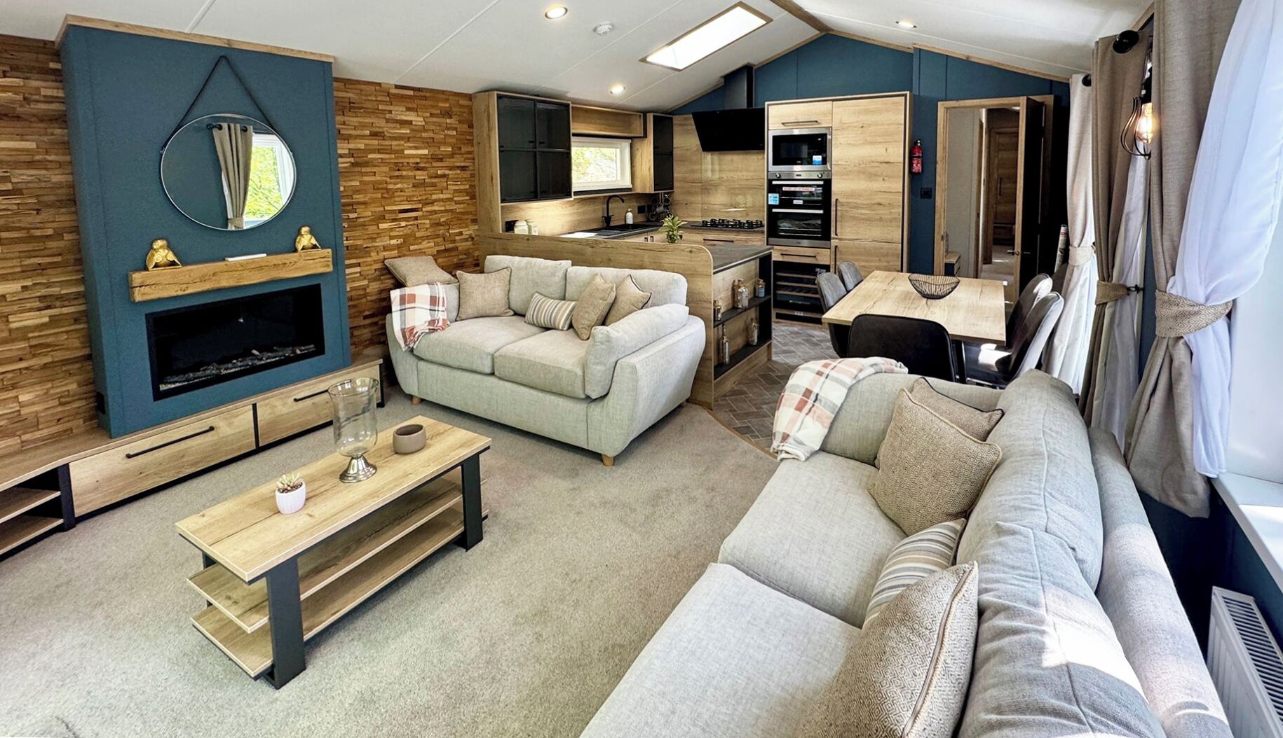 A modern living room with a sofa, coffee table, and a TV. There is a kitchen area with a dining table and chairs.