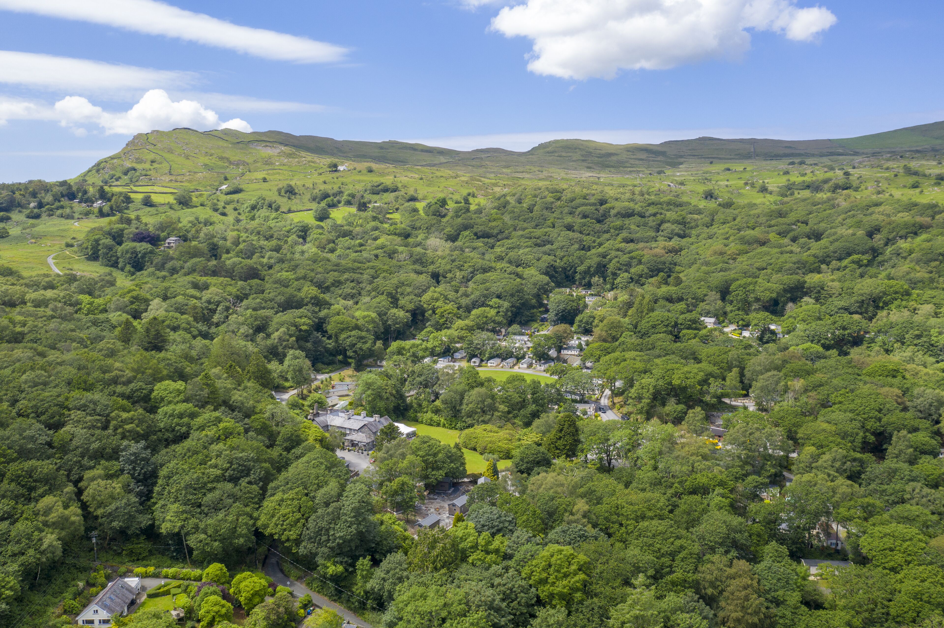 A lush green valley with scattered houses and a winding road.