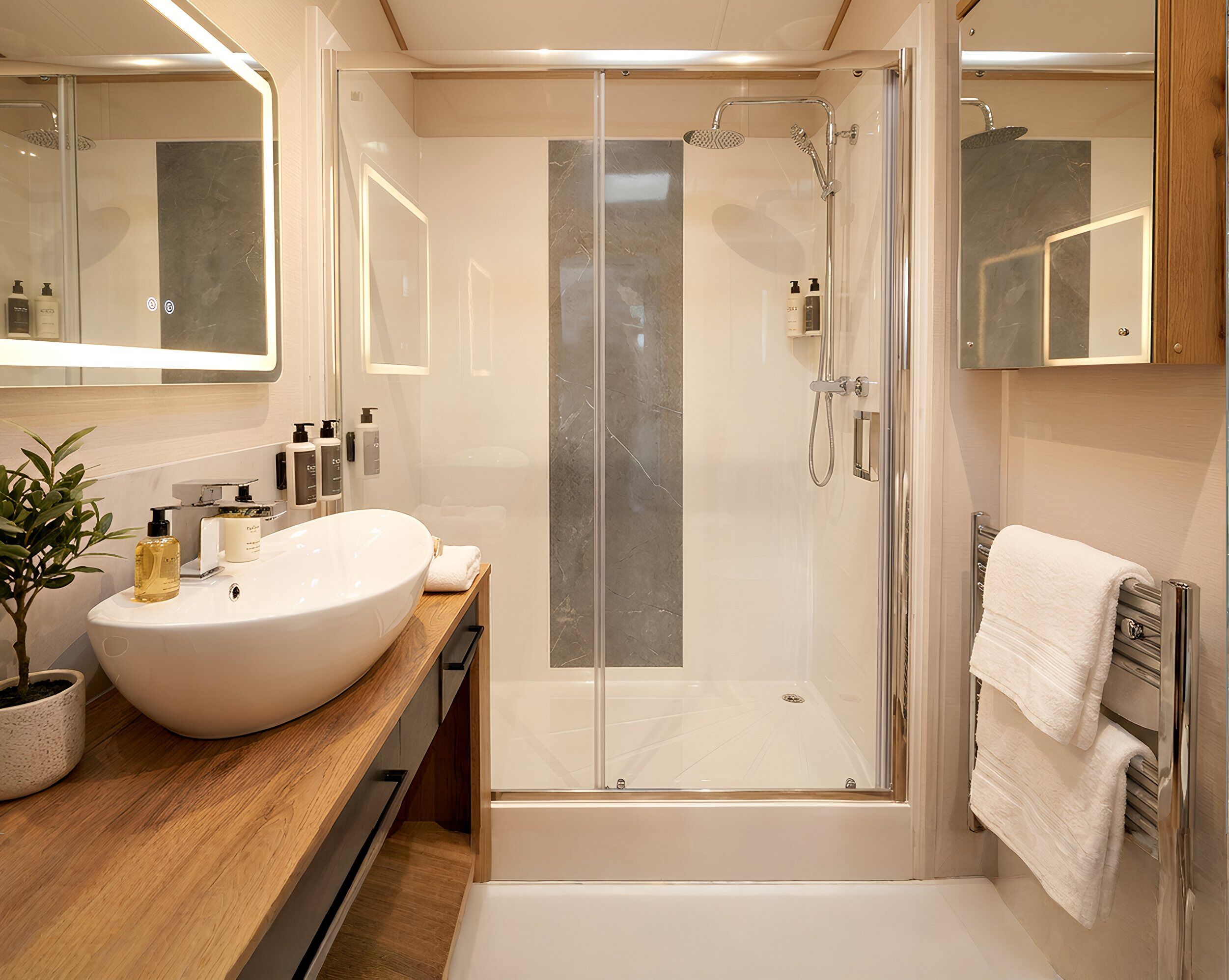 A modern bathroom with a large white sink, a glass-enclosed shower, and a wooden vanity.