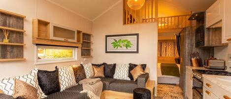 A cozy living area with a sofa, a coffee table, and a kitchen with a stove and cabinets.