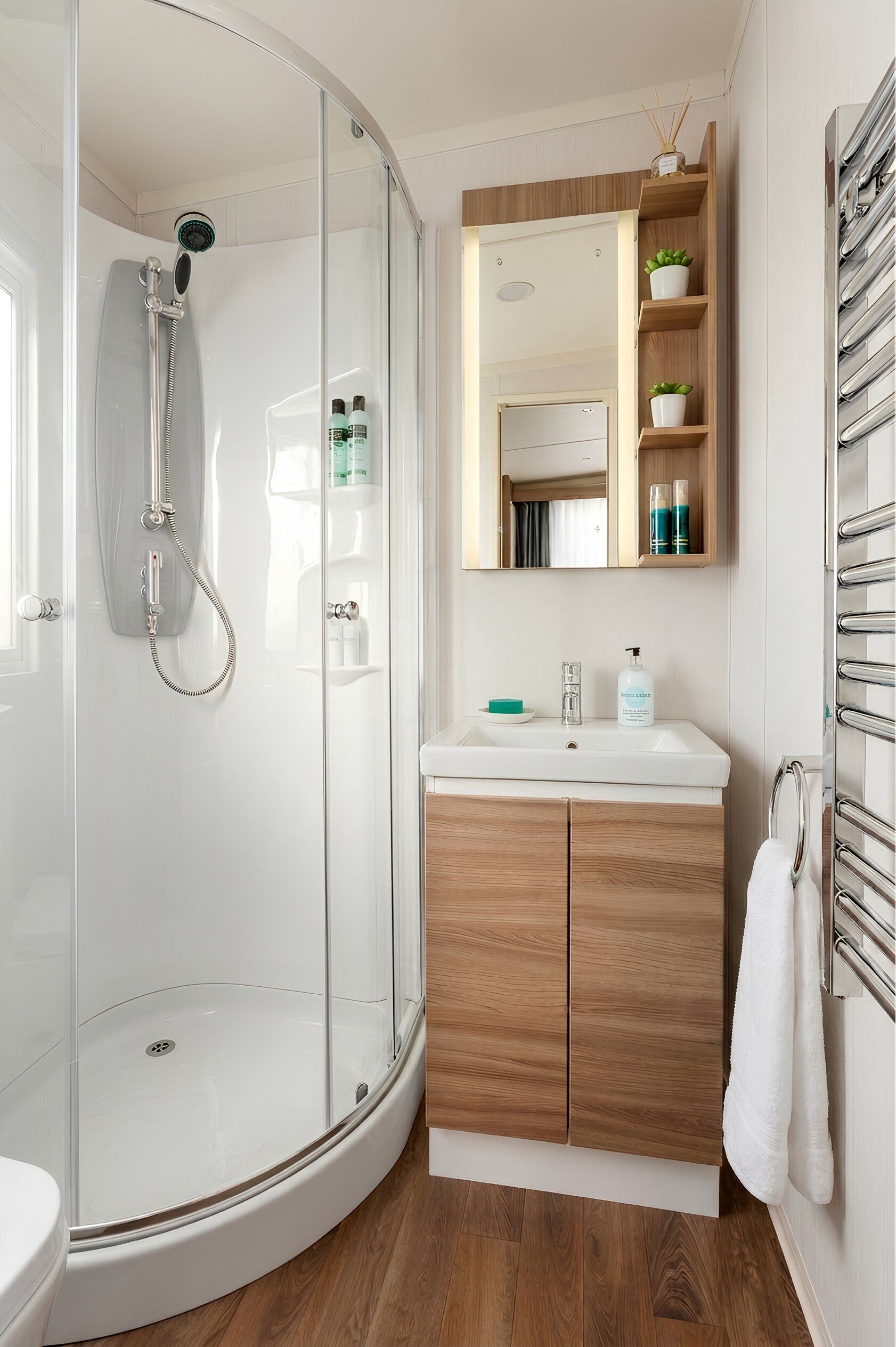 A modern bathroom with a glass-enclosed shower, a wooden vanity, and a mirror above the sink.