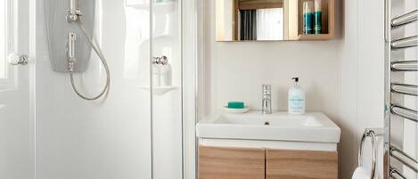 A modern bathroom with a glass-enclosed shower, a wooden vanity, and a mirror above the sink.