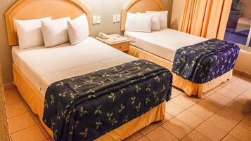 A hotel room with two beds, a nightstand, and a lamp.