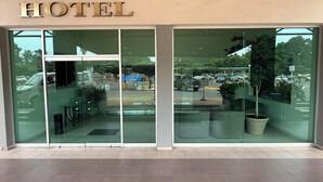 A hotel entrance with a glass facade, a sign above the doors, and a view of the parking area through the glass. - Plaza Inn Express (Tapachula)