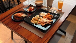 A dining table with two plates of food, a bowl, a cup, and a glass of orange juice. - Plaza Inn Express (Tapachula)