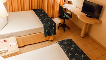 A hotel room with two beds, a desk with a television, a chair, and a lamp.